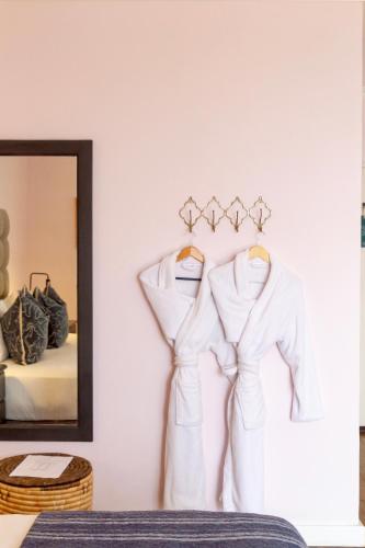 two dresses hanging on a wall next to a mirror at Royal Boutique Hotel in Cape Town
