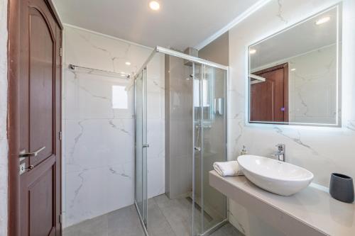Un baño blanco con lavabo y ducha. en Starry Sky Luxury Apartment 1, en Lefkimmi