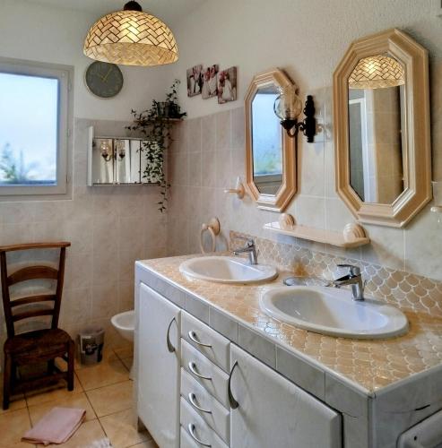 La salle de bains est pourvue de 2 lavabos, d'une chaise et de 2 miroirs. dans l'établissement La Pointe de Sel, à Salies-du-Salat