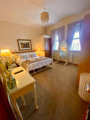 a bedroom with a bed and a table and a mirror at Station Cottage in Acle