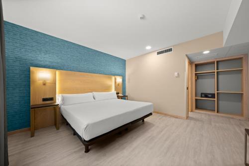 a bedroom with a large white bed and a blue wall at Hotel Zentral Ramiro I Oviedo in Oviedo