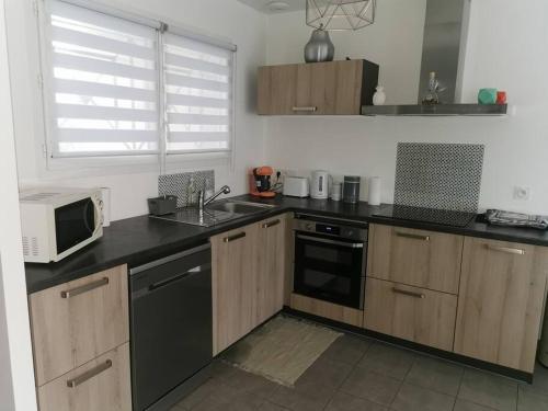 une cuisine avec un évier et un micro-ondes dans l'établissement Jolie maison entière avec 3 chambres centre ville, à Saint-André-de-Cubzac