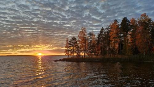 a sunset on a small island in a body of water at Villa Lähde Päijätsalon järvimaisemassa in Sysmä