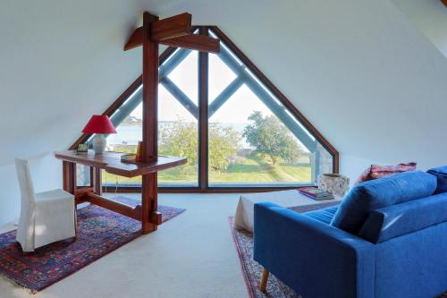 un salon avec un canapé bleu et une grande fenêtre dans l'établissement Maison Chevoir pieds dans l'eau, à Ploubazlanec