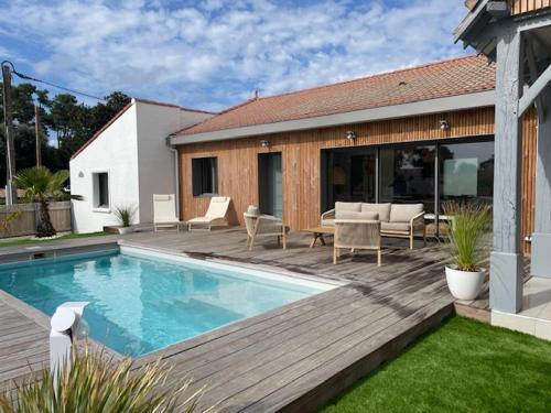une cour arrière avec une piscine et une terrasse en bois dans l'établissement L'écho des Vagues, à Jard-sur-Mer