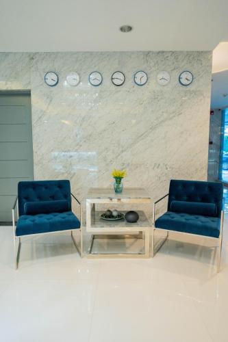 two chairs and a table and clocks on a wall at Stacia Hotel in Cebu City