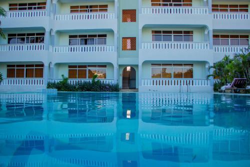 a building with a swimming pool in front of it at Nightingale Apartments Hotel Mombasa in Shanzu