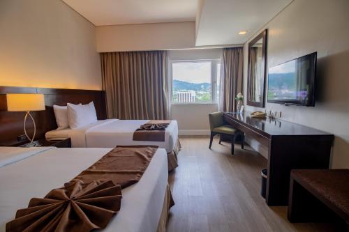 a hotel room with two beds and a desk at Harolds Hotel Cebu in Cebu City
