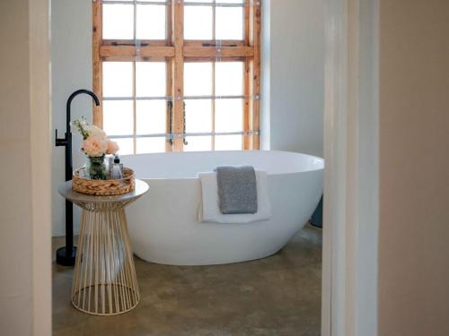Una bañera blanca en un baño con ventana. en Melkhout Farm Cottage, en Bonnievale