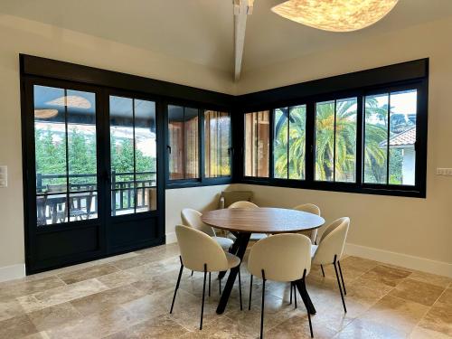 une salle à manger avec une table, des chaises et des fenêtres dans l'établissement Villa du Canon, à Lège-Cap-Ferret