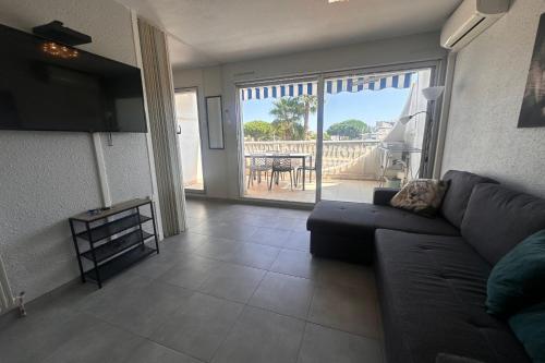 - un salon avec un canapé et une vue sur une terrasse dans l'établissement La Goélette - Appartement une chambre avec terrasse proche de la mer, au Grau-du-Roi