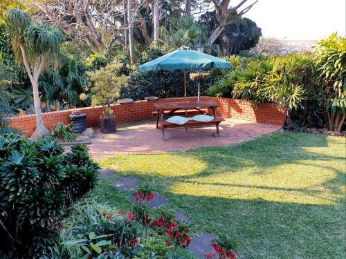 a table with an umbrella in a garden at Ridgeview Lodge in Durban