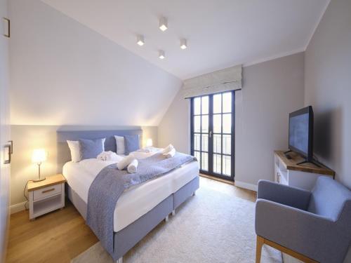 a bedroom with a bed and a tv and a chair at Reetland am Meer - LuxusPlus Reetdachvilla mit 4 Schlafzimmern und Kamin G09 in Dranske