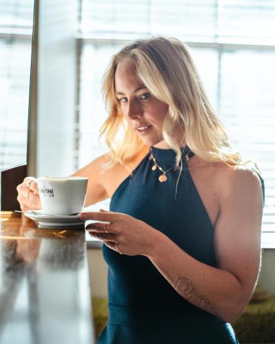 a woman in a dress holding a cup of coffee at Mannings Hotel in Truro