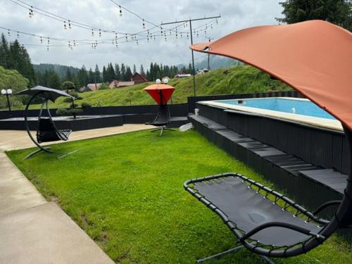 a patio with a chair and an umbrella next to a pool at Transylvania House in Arieşeni