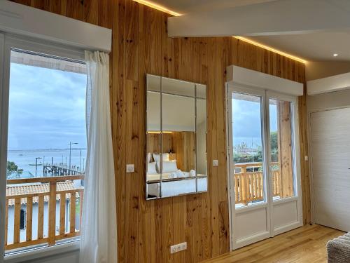 - une chambre avec des murs en bois et un balcon avec un miroir dans l'établissement Villa Louis - Grand Piquey, à Lège-Cap-Ferret