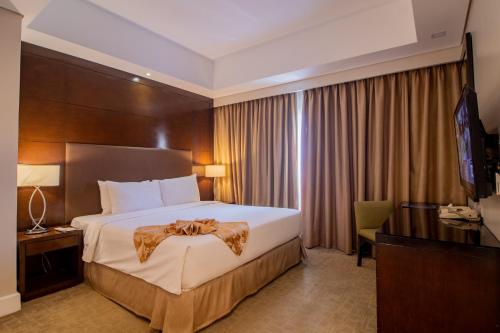 a hotel room with a large bed and a desk at Harolds Hotel Cebu in Cebu City