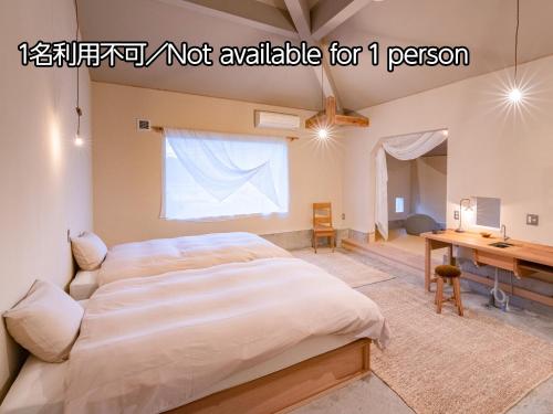 a bedroom with a large bed and a desk at Nisainoyuyado Asahiya in Beppu