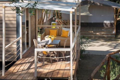 a gazebo with a couch and a table on a deck at Camping Il Capannino Glamping Village in Marina di Bibbona
