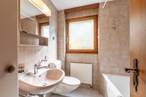 a bathroom with a sink and a toilet and a tub at Fabi`s Horu Lodge in Zermatt