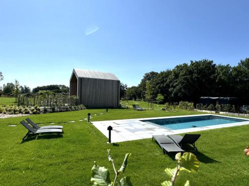 a yard with a pool and two chairs and a building at Durbuy Insolite - Panoramic Escape in Durbuy