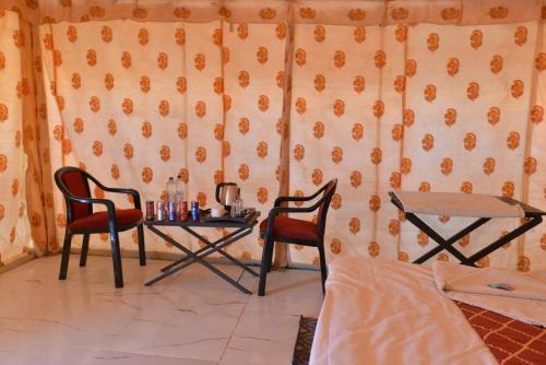 a room with a table and two chairs and a bed at Melody Moon Desert Camp & Resort in Jaisalmer