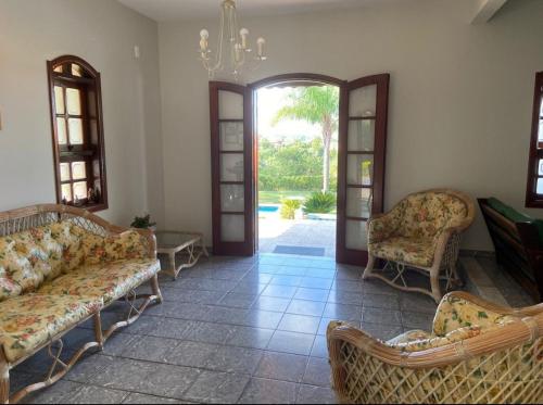 a living room with couches and chairs and an open door at Casa de Campo com Piscina in Itupeva