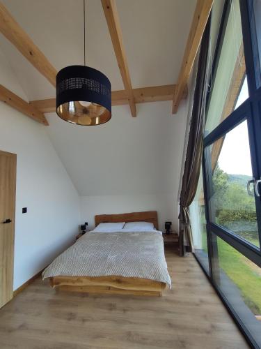 a bedroom with a bed and a large window at Domki na Lubczykowej in Ostre