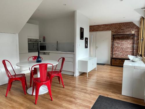 une cuisine avec une table et des chaises rouges dans une pièce dans l'établissement Le 128 - Maison de Charme, à Isneauville