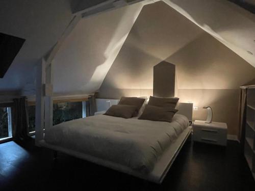 - une chambre avec un lit blanc et un plafond pointu dans l'établissement Le 128 - Maison de Charme, à Isneauville