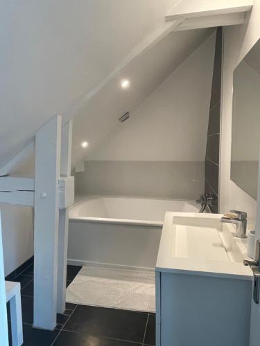 une salle de bain avec une baignoire blanche et un lavabo dans l'établissement Le 128 - Maison de Charme, à Isneauville