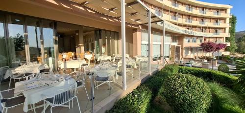 a restaurant with white tables and chairs on a building at Marmari Bay Hotel in Marmarion
