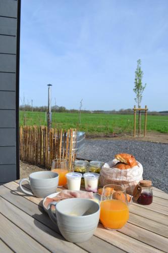 a wooden table with food and glasses of orange juice at Durbuy Insolite - Panoramic Escape in Durbuy