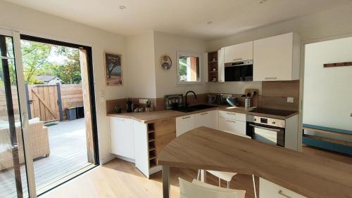 une cuisine avec des armoires blanches et une table en bois dans l'établissement La Brise des Bois pour 2 personnes, à Andernos-les-Bains