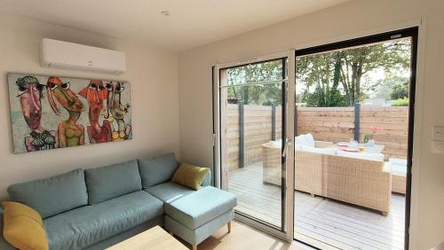 un salon avec un canapé et une porte coulissante en verre dans l'établissement La Brise des Bois pour 2 personnes, à Andernos-les-Bains