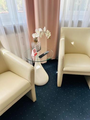 a room with two chairs and a glass table with a remote control at Landhaus Ambiente in Munich