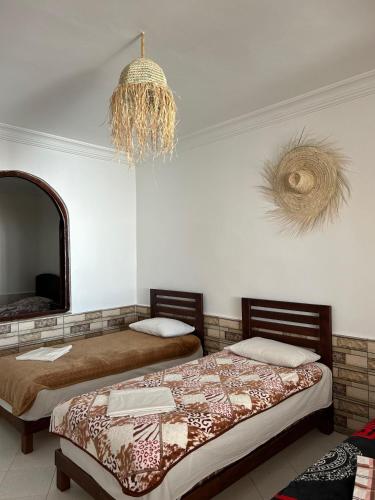 a bedroom with two beds and a mirror and a chandelier at Surfstay Taghazout 2 in Taghazout
