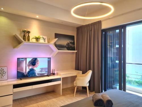 a bedroom with a tv and a desk with a chair at M city service suite KLCC in Kuala Lumpur