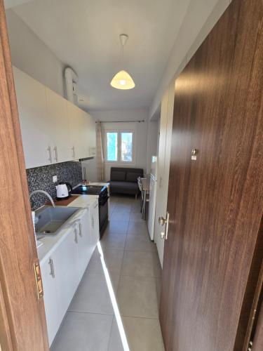 a kitchen with white cabinets and a wooden door at Αργέντη in Chios