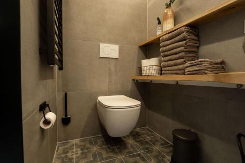 a bathroom with a toilet and a shelf with towels at Sfeervolle woning in boerderijstijl in Zelhem