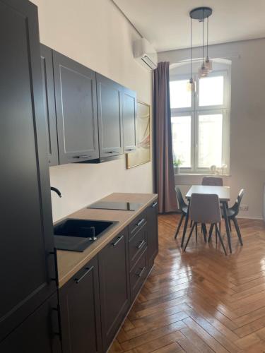 a kitchen with a sink and a table with chairs at Apartamenty Warszawska in Toruń