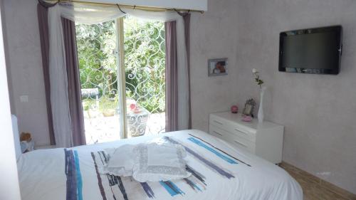 1 dormitorio con 1 cama, ventana y TV en Plein Soleil, en Mandelieu-la-Napoule