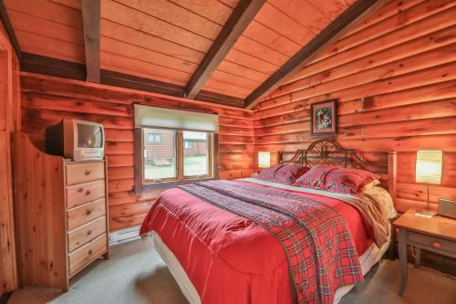 ein Schlafzimmer mit einem Bett und einem TV in einer Blockhütte in der Unterkunft 4 Bedroom Log Cabin with Stream and Great Location in Lanesville