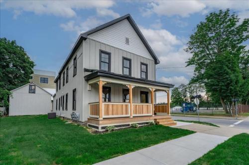 a white house with a porch on a street at Charming Newly Renovated House Next Door to Track in Saratoga Springs