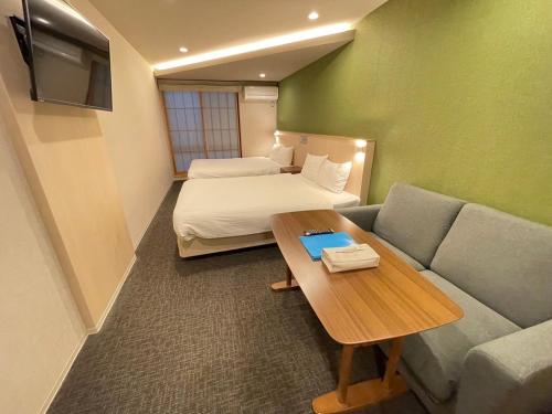 a hotel room with a couch and a bed and a table at HIZ HOTEL Gion-Shirakawa in Kyoto