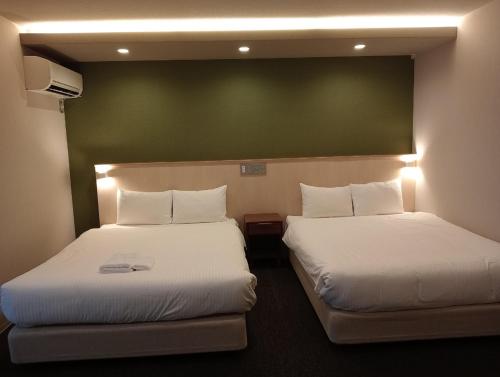 a hotel room with two beds and a green wall at HIZ HOTEL Gion-Shirakawa in Kyoto