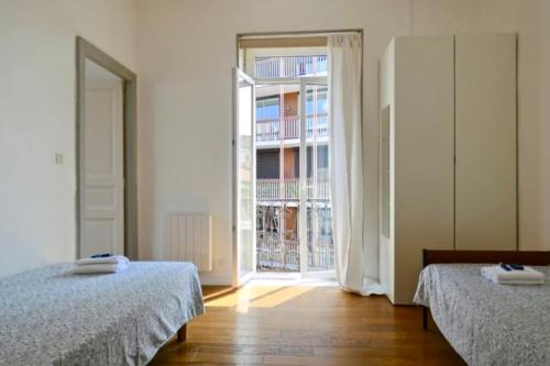Cette chambre comprend deux lits et une grande fenêtre. dans l'établissement Bel appartement hausmannien à Montpellier, à Montpellier