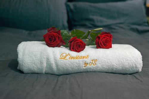 a towel with three red roses on a bed at L'instant in Duras