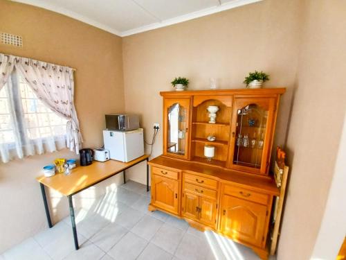 a kitchen with a wooden cabinet and a table at Sandy Pearl Cottage in Durban