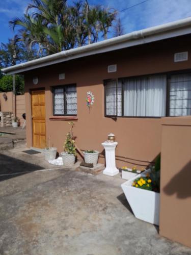 a house with potted plants in front of it at Sandy Pearl Cottage in Durban